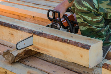 Man, builder, carpenter saws petrol chainsaw new hardwood timber, a building material, timber