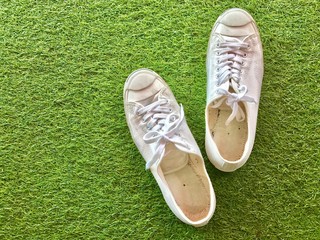Closeup A pair of white sneakers on green grass background.The concept of "Walking in the garden." Top view with Copy space.Selective focus.