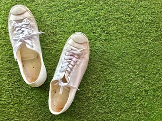 Closeup A pair of white sneakers on green grass background.The concept of "Walking in the garden." Top view with Copy space.Selective focus.