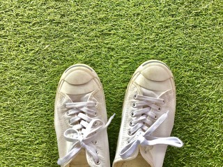 Closeup A pair of white sneakers on green grass background.The concept of "Walking in the garden." Top view with Copy space.Selective focus.