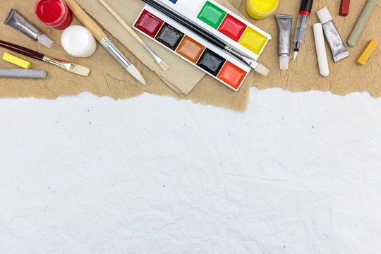 various colorful artistic drawing tools on recycled paper background, top view