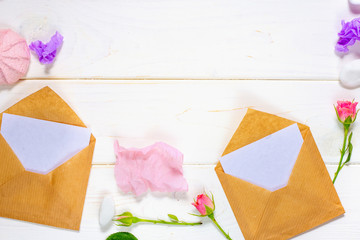 Envelope, paper blank and pink rose flower on white table top view in flat lay style for greeting card on Womans day.