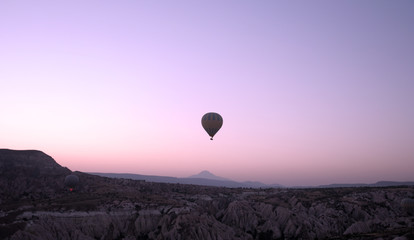 ballooning. A balloon flies in the sky in the rays of the rising sun. A bright sky, a haze, an extinct volcano on the horizon.