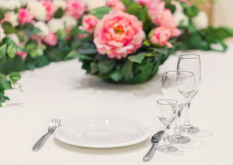 Served table for one person with a set of glasses, decorated with natural flowers. Event dinner