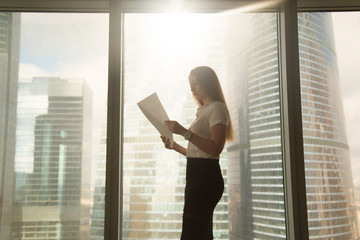 Busy serious businesswoman holding business document, reading report, looking through papers, doing...