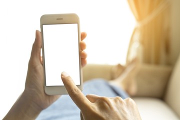 The view is cut off by the hands of a working woman who holds a smart phone with free space on the screen for your message. By her lying on the couch.