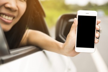 Women was sitting in the car.She was show smart phones. The mobile has a black space for your pictures and text.road trip, travel, destination technology and people concept.