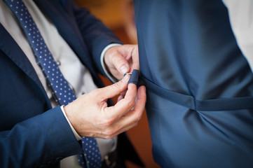 Mani maschili che regolano la fibbia del cinturino del gilet dello sposo