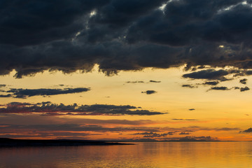 dark fluffy clouds on sky over sea during fiery sunset 