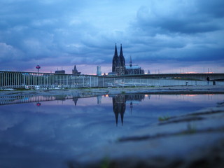 Kölner Dom reflektier in einer Pfütze bei Sonnenuntergang