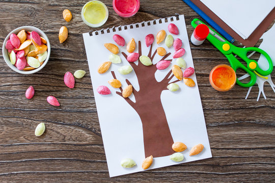 Postcard autumn tree with multi-colored leaves of a pumpkin leaf on a wooden background. Children's art project, craft for children. Craft for kids.
