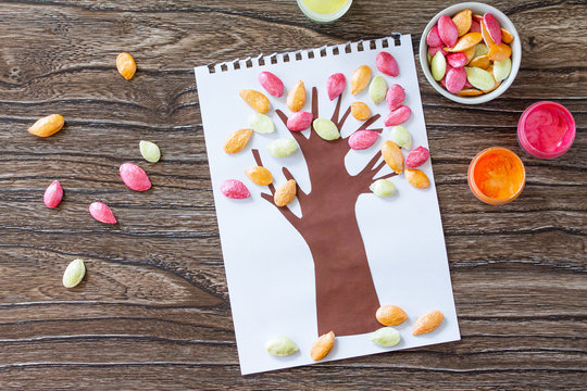 Postcard autumn tree with multi-colored leaves of a pumpkin leaf on a wooden background. Children's art project, craft for children. Craft for kids.