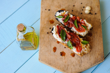 Italian bruschetta with roasted tomatoes, mozzarella cheese and herbs on a cutting board