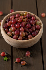 Red gooseberry in a bowl on wooden surface