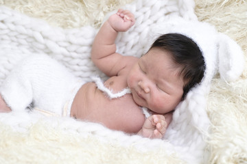 Portrait of Asia boy newborn is lay down on white fur background with bear .