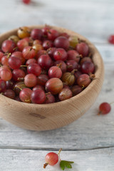 Red gooseberry in a bowl on wooden surface