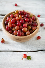 Red gooseberry in a bowl on wooden surface