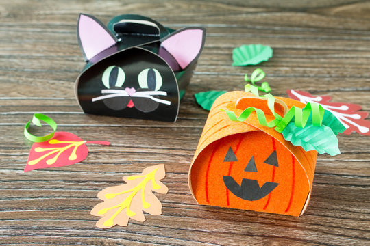 The child creates a gift box of a black cat of Halloween and a pumpkin of Halloween. Children's art project, craft for children. Craft for kids.