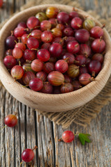 Red gooseberry in a bowl on wooden surface