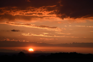 Obraz premium Sonnenuntergang mit kräftigenund intensiven Abendrot mit Windrädern im Hintergrund
