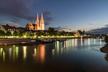 Beleuchtete Promenade in Regensburg mit Blick auf Dom und steinerne Brücke, Deutschland