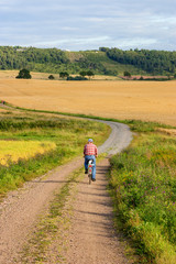 Fototapeta na wymiar Man cycling on a gravel road in a rural landscape