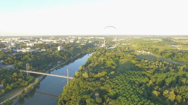 Aerial Paraplane hang glider in the air above river city canyon