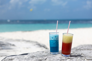 Colorful drinks on the beach. Turquoise water and white sand beach in the tropical vacation. Drinks composed to the right. Copy space.