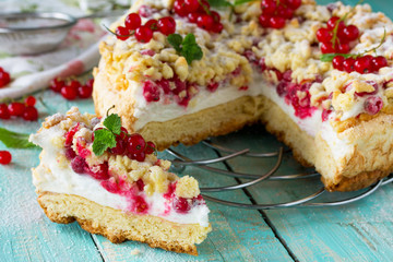 Sweet pastries. Cupcake with Pavlov meringue and fresh summer red currants on the kitchen wooden table. Summer baking concept.
