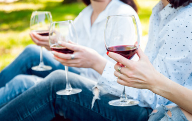 Young beautiful girls with glass of red wine in the park