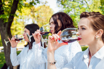 Young beautiful girls with glass of red wine in the park