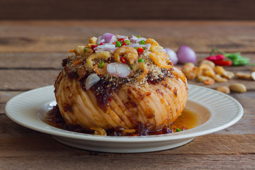 Santol salad on white plate.Spicy and sweet santol salad with Thai style salad dressing topping with dried coconut dried shrimp onion and chili.Delicious slice santol served with sweet and spicy sauce