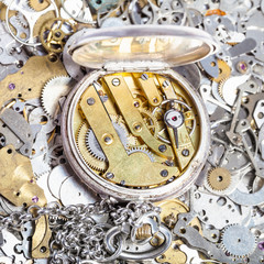 open retro pocket watch on heap of spare parts