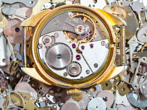 old golden watch on heap of clock spare parts