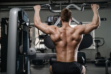 Fototapeta na wymiar Caucasian handsome fitness model training in the gym. Man on diet flexing muscles