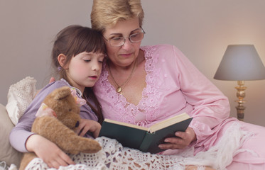 Grandmother is reading fairy tales to her granddaughter