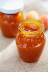 Apricot jam in glass jars with fresh fruit on table