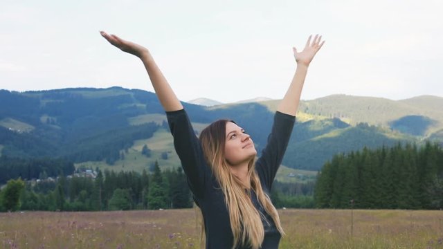 woman standing countryside meadow raised up hands raising standing turning around portrait mountains amazing landscape cheerful smiling breathe fresh air breathing slowmotion looking camera joyful
