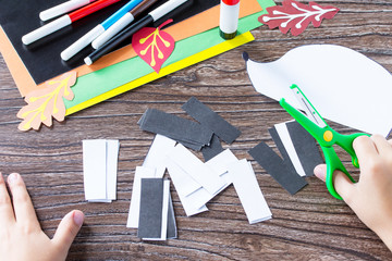 The child cuts out the details of the application. Autumnal application of a hedgehog and deciduous leaves. Children's Art Project, needlework, crafts for kids.