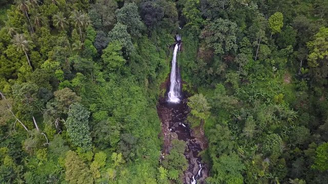 Beautiful aerial view footage of Gitgit waterfall and tropical forest, shot from a drone flying backward in Bali, Indonesia. Shot in 4k resolution