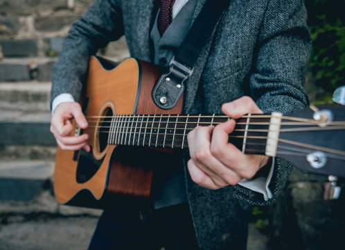 Man's hands playing acoustic guitar. Background