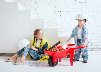 Little girl and boy with wheelbarrow on the white background. Construction