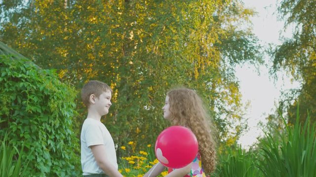 Little boy gift his girlfriend balloons with heart in summer park. Valentines day background.