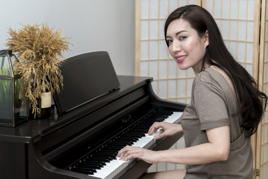 Young beautiful woman smiling playing piano
