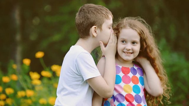 Little friends whispering in summer park. Slow motion