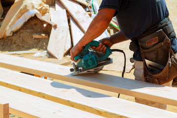 Carpenter using circular saw for cutting wooden boards. Construction details of male worker