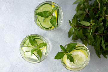 Obraz premium Refreshing summer drink-antioxidant with lemon, mint and cucumber on grey background.