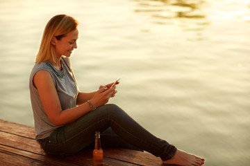  Smile woman sitting on dock and looking at celphone
