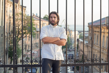 portrait of bearded man in white shirt , urban background, hipster posing on the bridge 