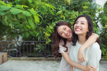 Naklejka premium Asian sisters hugging and smiling in the park.